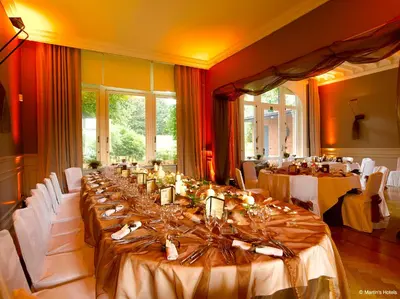 a large room with long tables with white chairs at Martin's Manoir in Genval