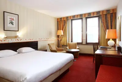 a hotel room with a bed and a desk at NH Mechelen in Mechelen
