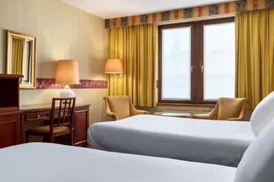 a hotel room with two beds and a desk at NH Mechelen in Mechelen