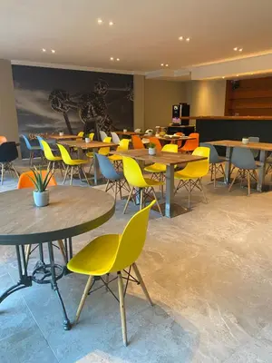 a classroom with tables and chairs with yellow chairs at Sleep & Go Brussels Expo Hotel in Brussels