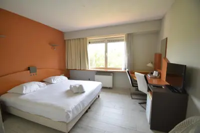 a hotel room with a bed and a desk and a television at Sleep & Go Brussels Expo Hotel in Brussels