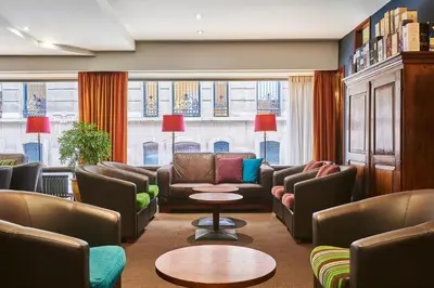a waiting room with couches and tables and windows at Theater Hotel in Antwerp