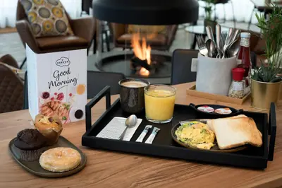 a tray of breakfast foods and a glass of orange juice at PREMIER SUITES Antwerp in Antwerp