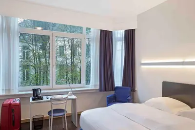 a hotel room with a bed and a desk and window at Hôtel Argus by happyCulture in Brussels