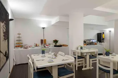 a restaurant with white tables and chairs and a kitchen at Hôtel Argus by happyCulture in Brussels