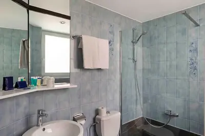 a blue tiled bathroom with a toilet and a sink at Hôtel Argus by happyCulture in Brussels