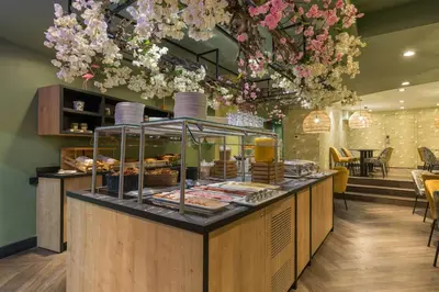 a bakery with a counter with pastries and flowers at Leonardo Hotel Antwerpen in Antwerp