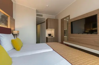 a bedroom with a large bed with a television on the wall at Leonardo Hotel Antwerpen in Antwerp