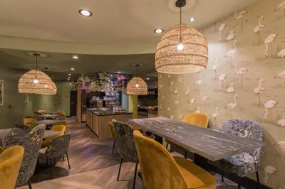 a restaurant with tables and chairs and pink flamingos on the wall at Leonardo Hotel Antwerpen in Antwerp