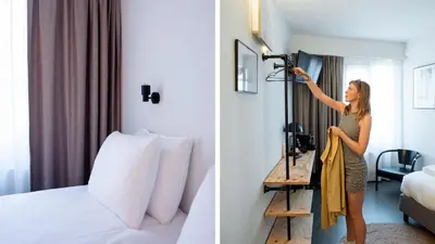 a woman standing in a hotel room holding a robe at Hotel National Antwerp in Antwerp