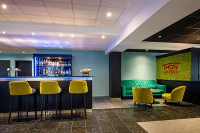 a bar with yellow chairs and a green wall at Thon Hotel Brussels Airport in Diegem