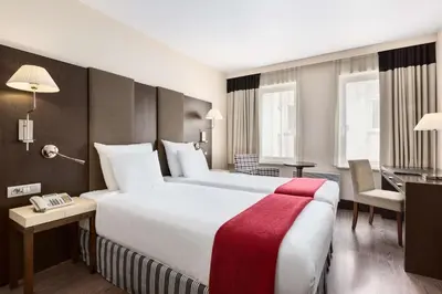 a hotel room with a large bed and a desk at NH Brussels Grand Place Arenberg in Brussels