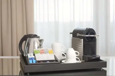 a tray with a coffee maker and cups on a table at NH Brussels Grand Place Arenberg in Brussels