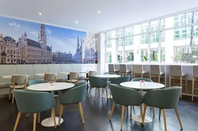 a restaurant with tables and chairs and a large window at NH Brussels Grand Place Arenberg in Brussels