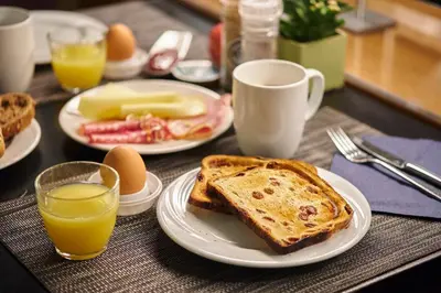 a table with plates of toast and eggs and orange juice at Holiday Inn Gent Expo by IHG in Ghent