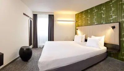 a hotel room with a large white bed and a green wall at Best Western Hotel Wavre in Wavre