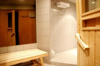 a bathroom with a shower with a bench in it at NH Collection Gent in Ghent