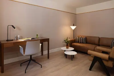 a living room with a couch and a desk at NH Collection Gent in Ghent