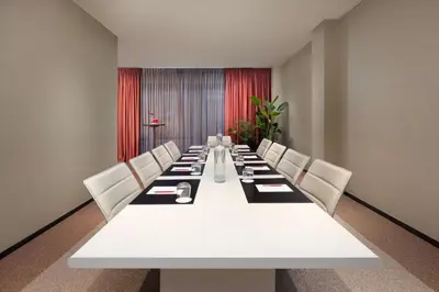 a conference room with a long white table and white chairs at NH Collection Gent in Ghent