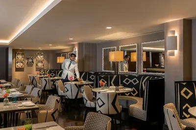 a restaurant with tables and two men standing in the middle at Hotel Amigo, a Rocco Forte Hotel in Brussels