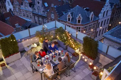 a group of people sitting at tables on a patio at night at Hotel Amigo, a Rocco Forte Hotel in Brussels