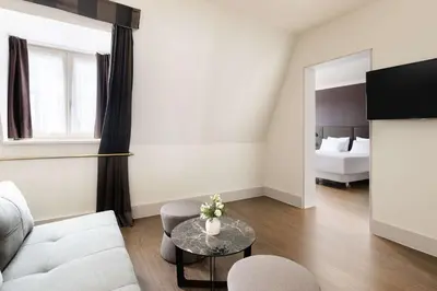 a living room with a couch and a table and a bed at NH Brussels Carrefour de L’Europe in Brussels