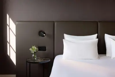 a bedroom with a bed with white pillows and a table at NH Brussels Carrefour de L’Europe in Brussels