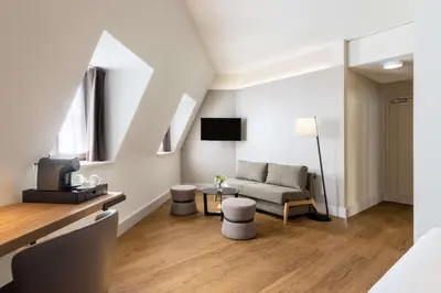 a living room with a couch and a tv at NH Brussels Carrefour de L’Europe in Brussels