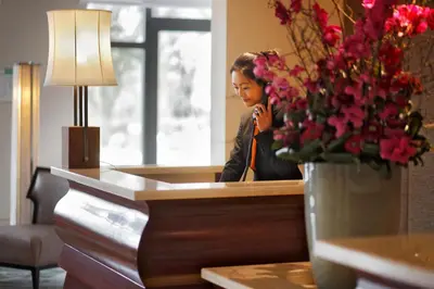 a woman sitting at a desk talking on a cell phone at Tangla Hotel Brussels in Brussels