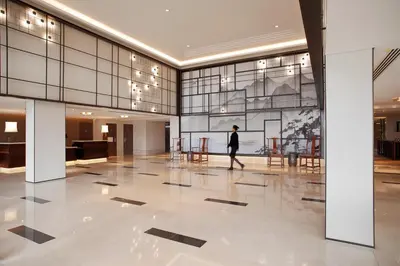 a man walks through a large lobby with glass walls at Tangla Hotel Brussels in Brussels