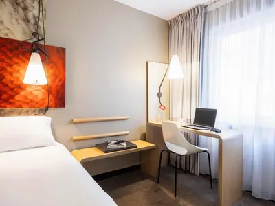 a hotel room with a bed and a desk with a laptop at Ibis Brussels City Centre in Brussels