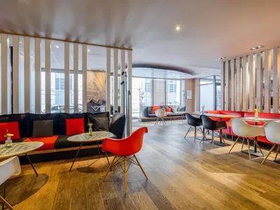 a living room with a couch and tables and chairs at Ibis Brussels City Centre in Brussels