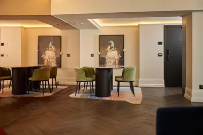 a room with a table and chairs and paintings at Cardo Brussels, Autograph Collection in Brussels