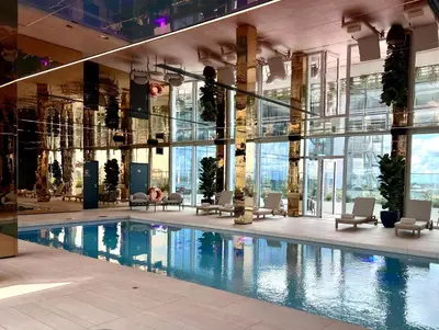 a swimming pool in a building with chairs and windows at Cardo Brussels, Autograph Collection in Brussels
