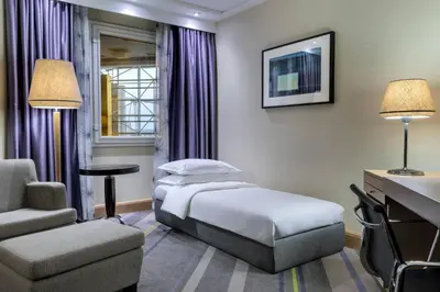 a hotel room with a bed and a chair and a desk at Sheraton Brussels Airport Hotel in Zaventem