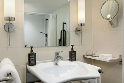 a white bathroom with a sink and a mirror at Sheraton Brussels Airport Hotel in Zaventem