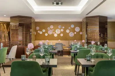 a dining room with tables and green chairs at Sheraton Brussels Airport Hotel in Zaventem