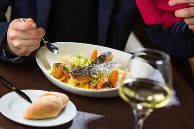 a person eating a bowl of food with a glass of wine at Sheraton Brussels Airport Hotel in Zaventem