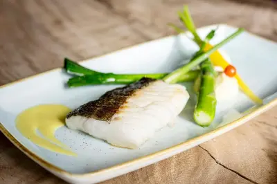 a plate of food with a piece of fish and asparagus at Holiday Inn Hotel Brussels Airport by IHG in Diegem