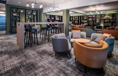 a lobby with chairs and tables and a bar at Holiday Inn Hotel Brussels Airport by IHG in Diegem