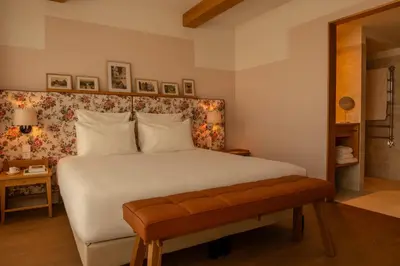 a bedroom with a large white bed with a bench at 9Hotel Chelton in Brussels