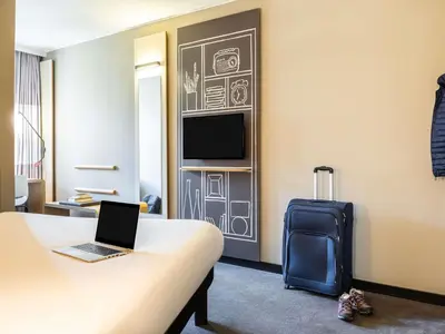 a hotel room with a bed and a laptop and a suitcase at ibis Hotel Brussels off Grand'Place in Brussels