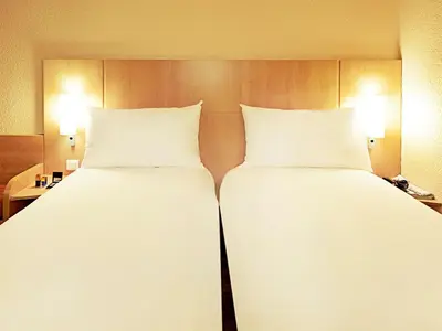two beds in a hotel room with white sheets and pillows at ibis Hotel Brussels Expo Atomium in Brussels