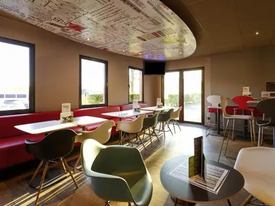 a restaurant with tables and chairs and a laptop at ibis Hotel Brussels Airport in Diegem
