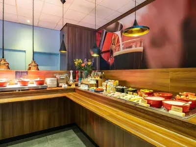 a restaurant with a counter with food on it at ibis Gent Centrum Opera in Ghent