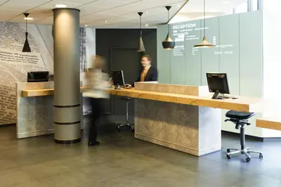 a man is standing at a desk in an office at ibis Gent Centrum St. Baafs Kathedraal in Ghent