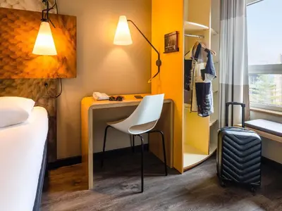 a room with a desk and a chair and a bed at ibis Leuven Centrum in Leuven