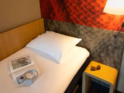 a small bed with a pillow and a box on it at ibis Leuven Centrum in Leuven