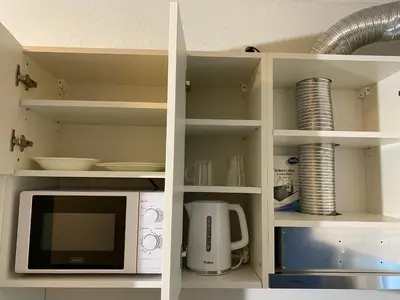 a white cabinet with a microwave and a coffee maker at Hotel Fauwater in Kasterlee