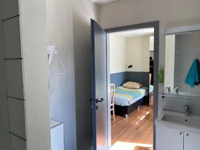 a bedroom with a bed and a door leading to a bathroom at Hotel Fauwater in Kasterlee